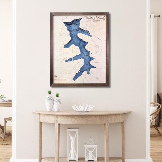 Custom wooden map of Mohawk Lake on a wall above a wooden table in a room.