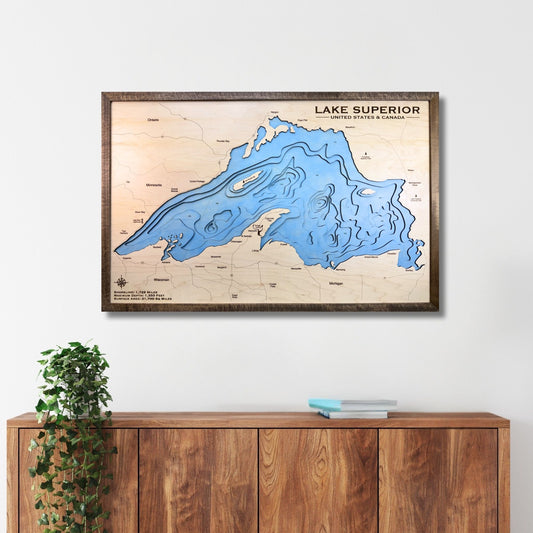 Wooden framed map of Lake Superior on a white wall above a wooden cabinet.