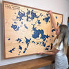 Woman hanging a large custom map that has many different lakes on it. 