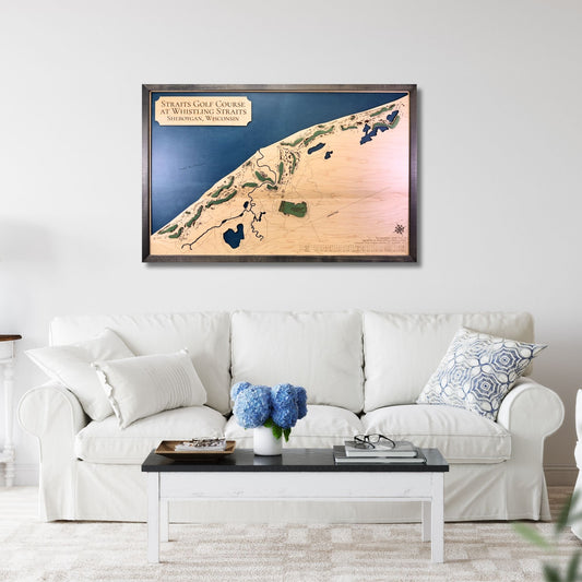 A large framed wooden map of Straits Golf Course hanging on a living room wall above a couch. 