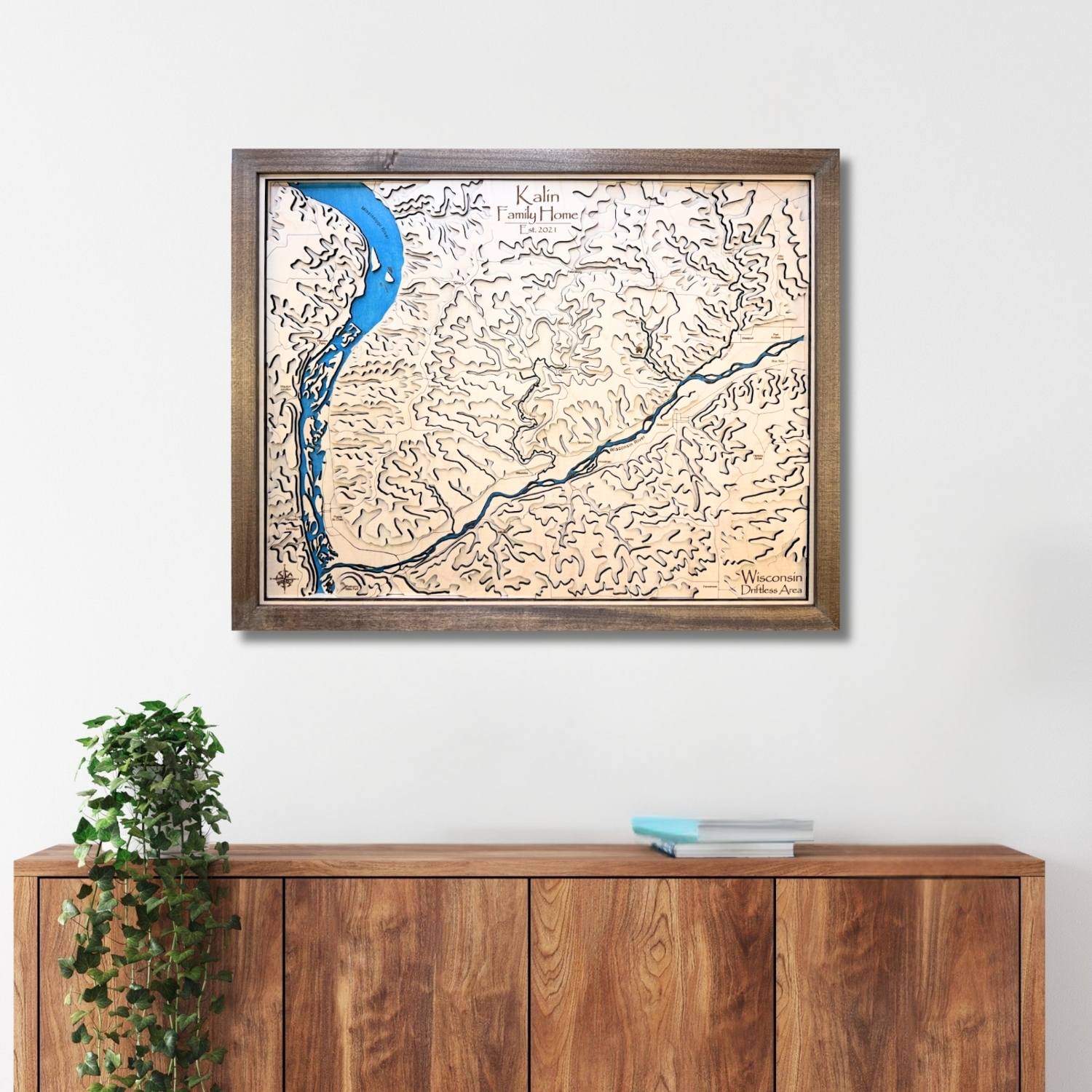 Framed topographic map of the Driftless Area on a white wall above a wooden cabinet.