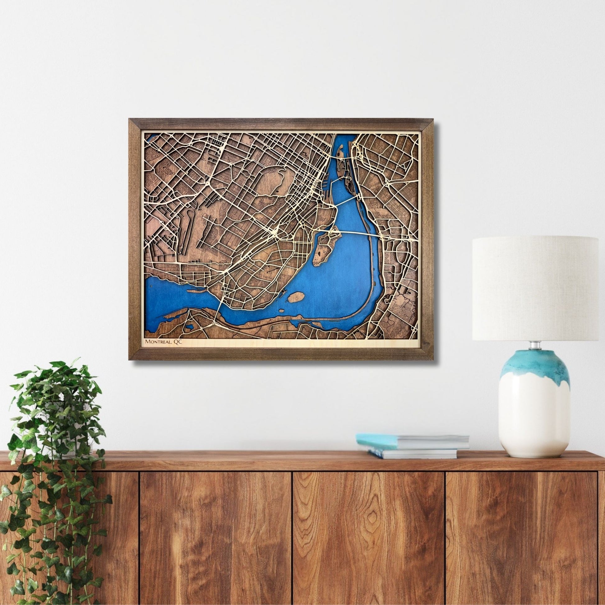 Framed wooden map of Montreal hanging on a wall above a console. 