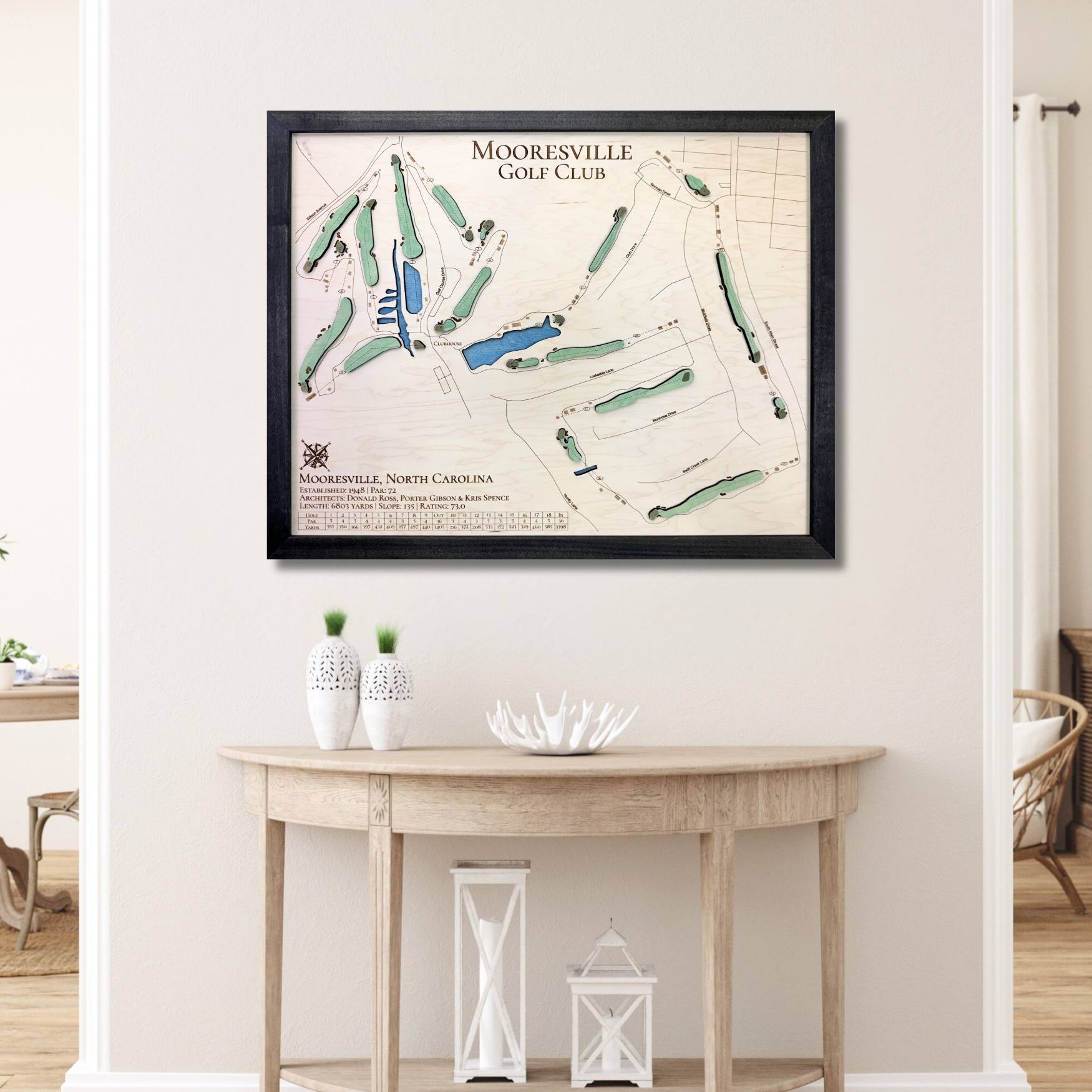 Framed 3D wooden map of Mooresville Golf Club on a wall above a wooden table.
