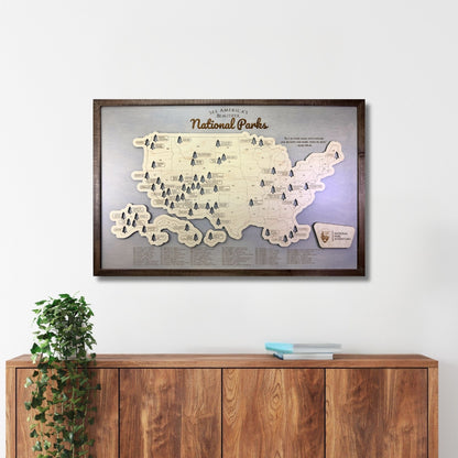 Framed wooden map of National Parks on a wall above a wooden cabinet.