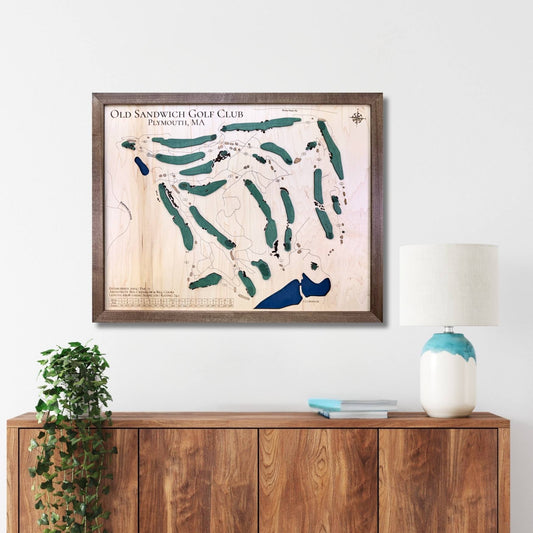 Framed wooden map of Old Sandwich Golf Club above a wooden console table with decor items.