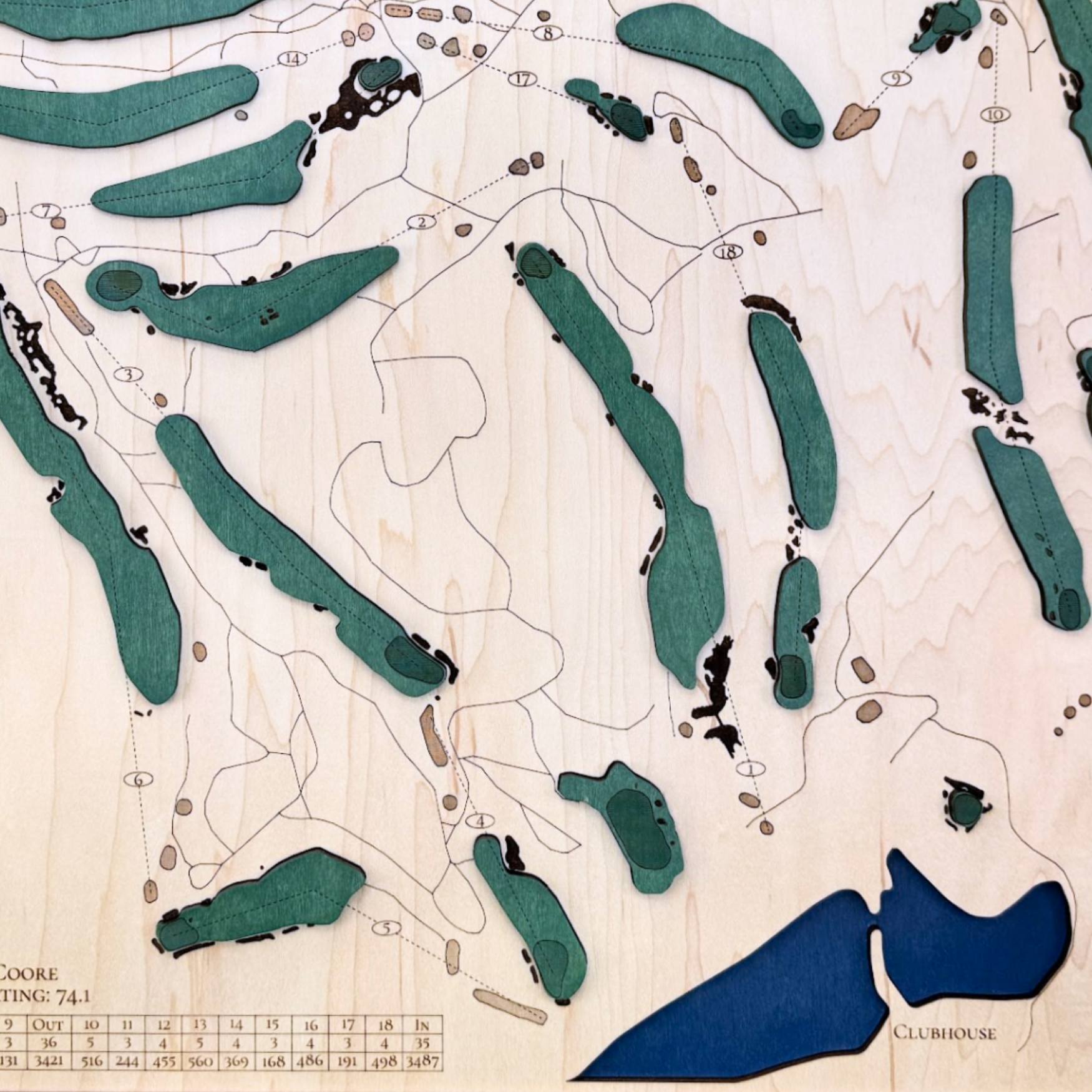 Close up of wooden golf course map with green fairways, blue water hazards, and engraved text. 