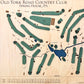 Close up of wooden golf course map with green fairways, blue water hazards, and engraved text. 
