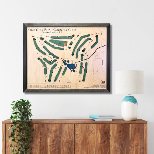 Framed wooden map of Old York Road Country Club on a wall above a wooden console table.