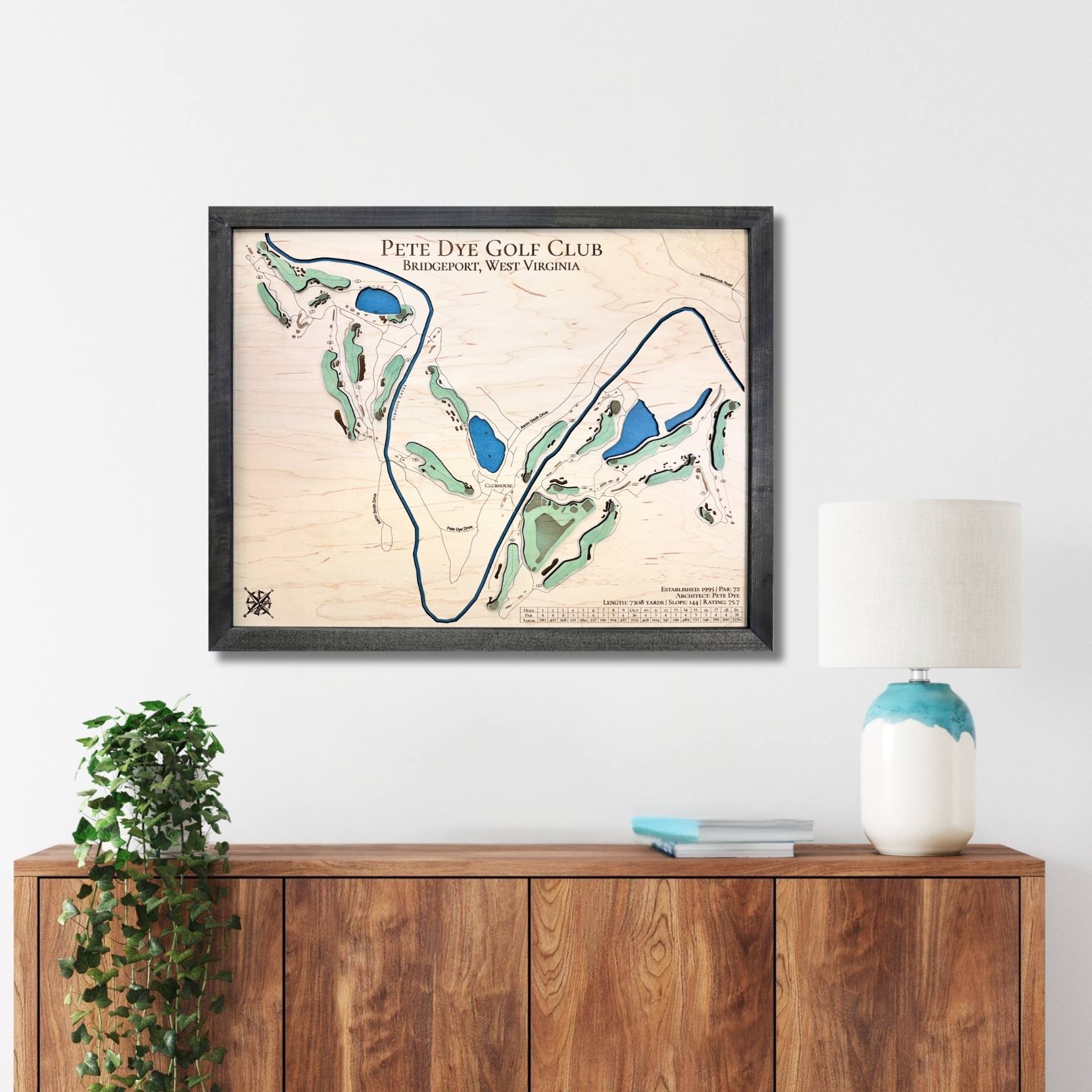 Framed golf course map on a wall above a wooden console table.