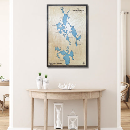 Framed custom map of Portage Lakes on a wall above a wooden table.