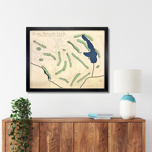 Framed golf course map of Quail Hollow, NC on a wall above a wooden console table.