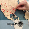A hand pushing in the red pins into the world travel map. 