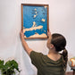 A woman hanging the Sandusky Bay Island Map on a wall.
