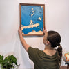 Woman hanging a wooden map of Lake Erie Islands and Sandusky Bay. 
