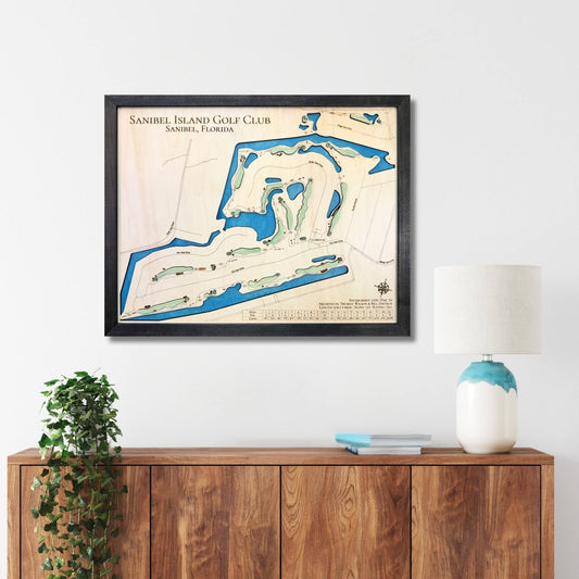 Framed map of Sanibel Island Golf Club on a wall above a wooden console table.