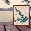 Framed map of Smith Mountain Lake on a wooden dock with a lake and mountains in the background.