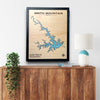 Framed single water layer map of Smith Mountain Lake on a wooden surface with a lamp and plant.