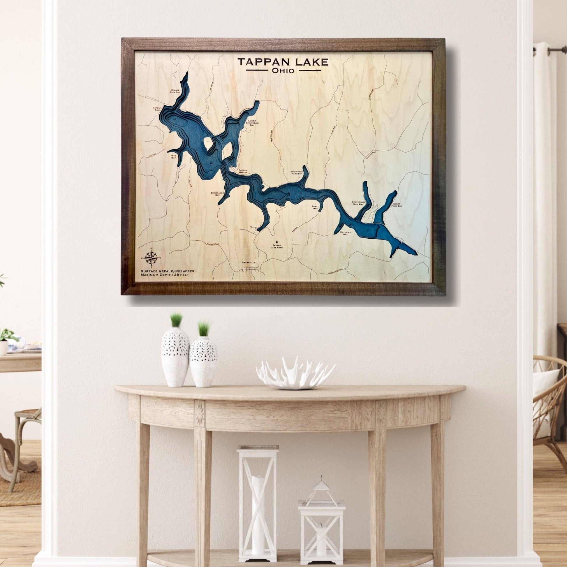 Framed multilayer wooden map of Tappan Lake, Ohio on a wall above a wooden table.