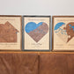 Three maps sit in a row on a table: a house-shaped map and two variations of the heart-shaped maps. All maps have attached icons. 
