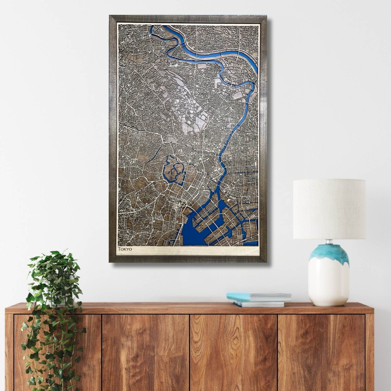 Framed city map of Tokyo on a wall above a wooden cabinet with decorative items.