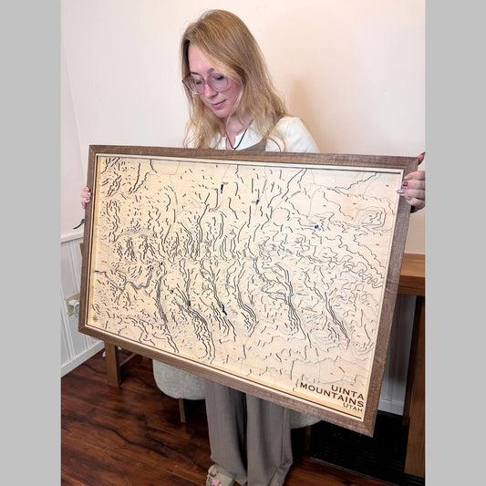 Woman holding a large framed topographic map of the Uinta Mountains, Utah.