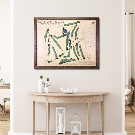 Framed wooden golf map of Tripoli Country Club on a wall above a wooden table.