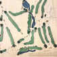 Close up of wooden golf course map with green fairways, blue water hazards, and engraved text. 