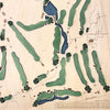 Close up of wooden golf course map with green fairways, blue water hazards, and engraved text. 