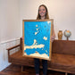 Woman holding a map of a Lake Erie Islands map with a couch and decorative items in the background. 