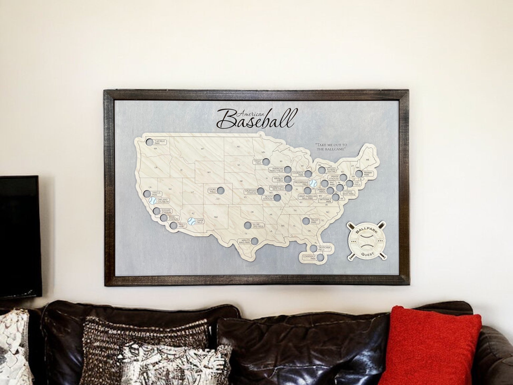 Major League baseball stadium travel map hangin on the wall above a couch. 