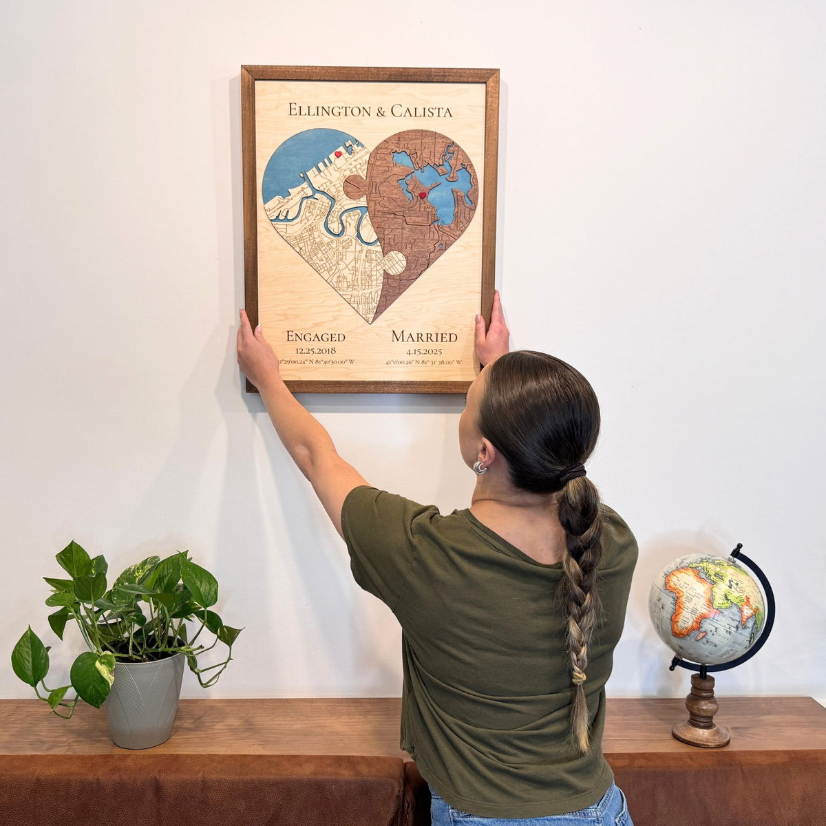 Woman hanging a custom two locations heart map on the wall. 