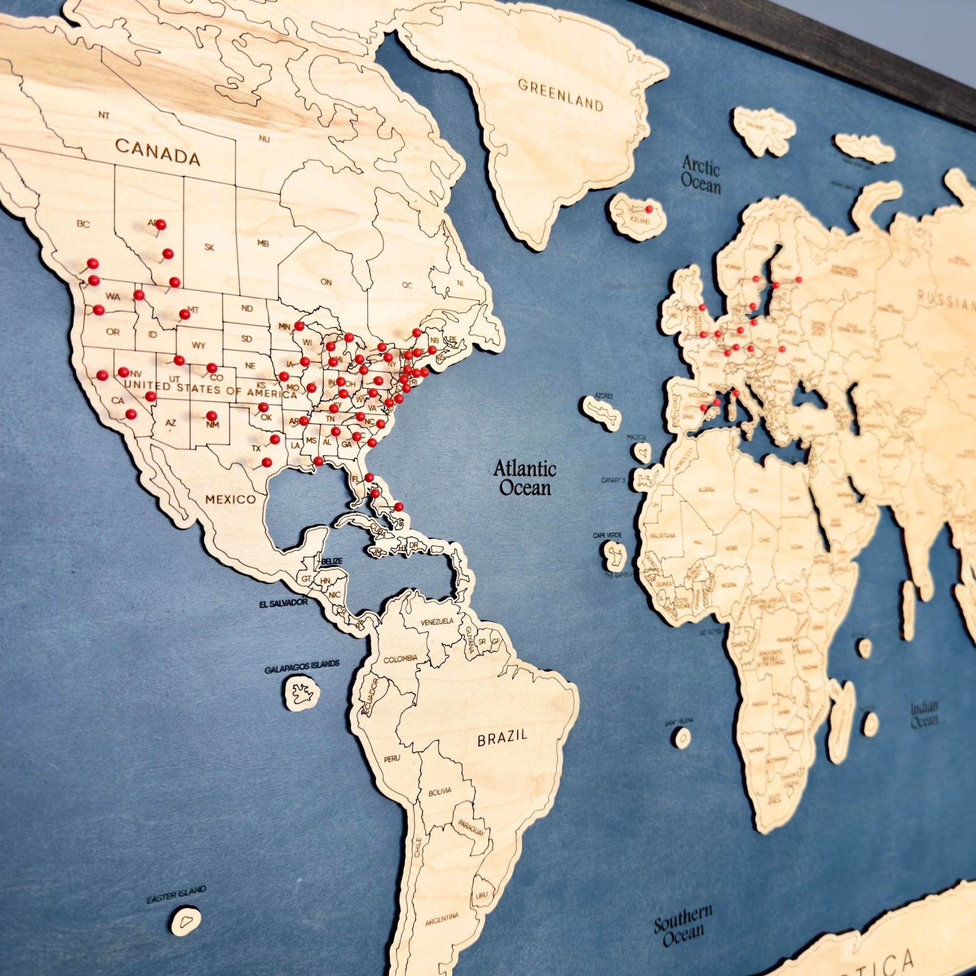 Close up sideview of red pins marking travel locations on a world travel map. 